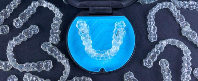 Plastic case with invisible transparent orthodontic retainers invisalign on black background. Aligner brackets or braces dental container